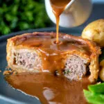 Cut open traditional Scotch meat pie served with lamb gravy.