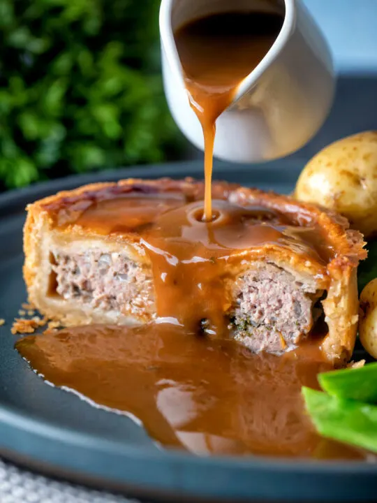 Cut open traditional Scotch meat pie served with lamb gravy.