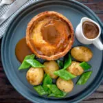 Overhead traditional Scotch meat pie served with lamb gravy, potatoes and runner beans.