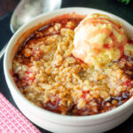 Individual strawberry crumble with balsamic vinegar served with vanilla ice cream.