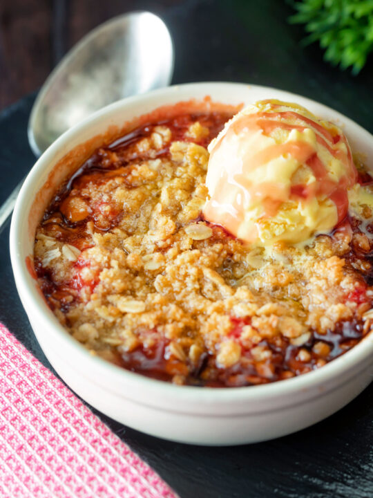 Individual strawberry crumble with balsamic vinegar served with vanilla ice cream.