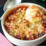 Individual strawberry crumble with balsamic vinegar served with vanilla ice cream featuring a title overlay.