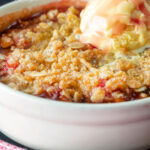 Close up individual strawberry crumble with balsamic vinegar served with vanilla ice cream featuring a title overlay.