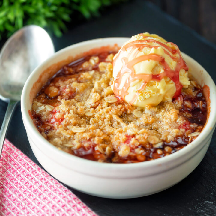 Individual strawberry crumble servings with balsamic vinegar and ice cream.