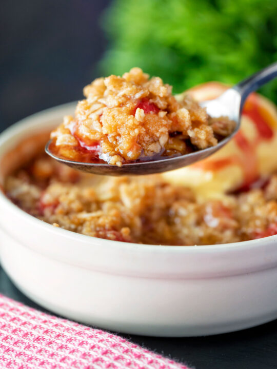 Individual strawberry crumble with balsamic vinegar on a spoon.