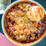 Overhead individual strawberry crumble with balsamic vinegar served with vanilla ice cream.