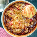 Overhead individual strawberry crumble with balsamic vinegar served with vanilla ice cream featuring a title overlay.