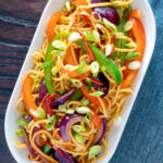 Overhead stir fried sweet chilli noodles with peppers, red onions garnished with spring onion featuring a title overlay.