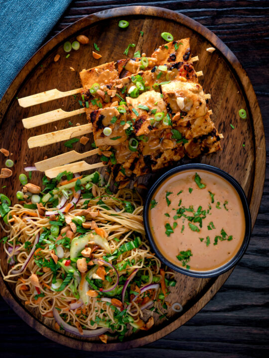 Overhead tofu satay with a peanut sauce and noodle salad.