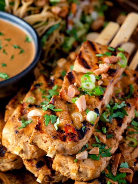 Close up tofu satay with a peanut sauce and noodle salad.