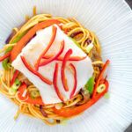 Overhead cod loin cooked en papillote served with sweet chilli noodles.