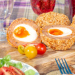 Oven baked scotch eggs cut open to show a jammy yolk.