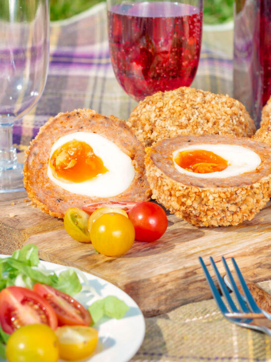 Oven baked scotch eggs cut open to show a jammy yolk.