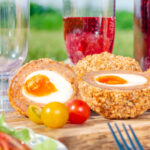Picnic spread with oven baked scotch eggs cut open to show a jammy yolk.