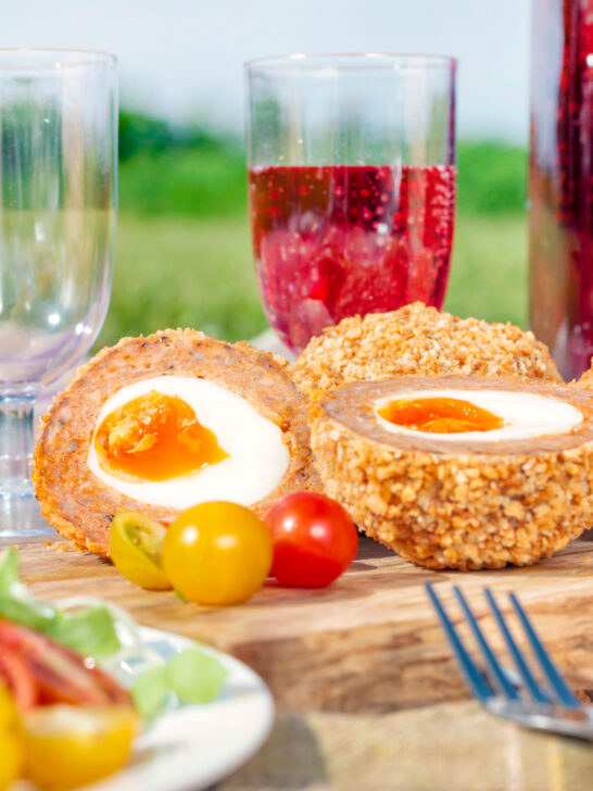 Picnic spread with oven baked scotch eggs cut open to show a jammy yolk.