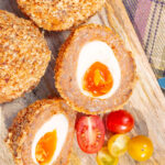 Close up overhead oven baked Scotch eggs with cherry tomatoes.