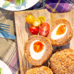 Close up overhead oven baked Scotch eggs with cherry tomatoes.