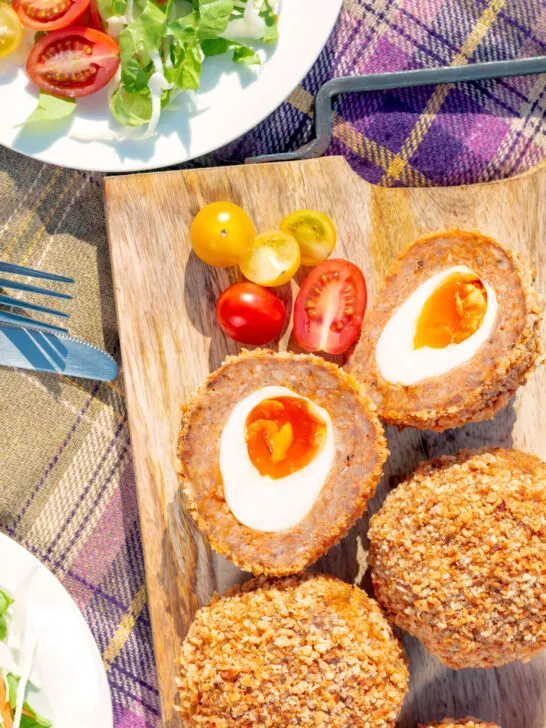 Close up overhead oven baked Scotch eggs with cherry tomatoes.