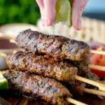 Lime wedges being squeezed over Lebanese influenced beef kofta kebabs.