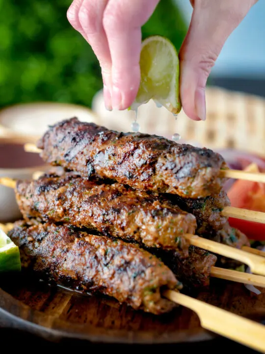 Lime wedges being squeezed over Lebanese influenced beef kofta kebabs.