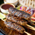 Minced beef kofta kebabs served with salad, pita bread and sauces featuring a title overlay.