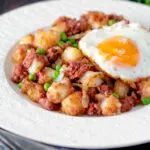 Canned corned beef hash with fried egg and peas.