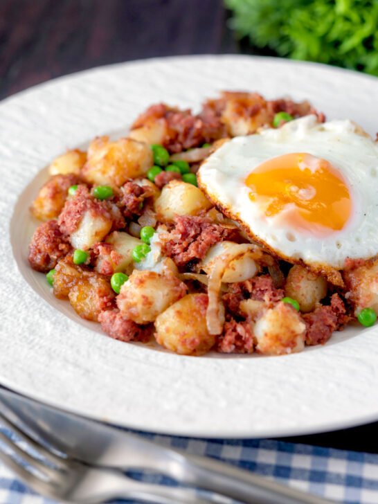 Canned corned beef hash with fried egg and peas.