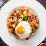 Overhead canned corned beef hash with fried egg and peas featuring a title overlay.