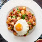 Overhead canned corned beef hash with fried egg and peas featuring a title overlay.