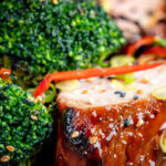 Close up char siu pork tenderloin, or Chinese BBQ pork served with broccoli stir fry and chilli featuring a title overlay.