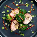 Overhead char siu pork tenderloin, or Chinese BBQ pork served with broccoli stir fry featuring a title overlay.