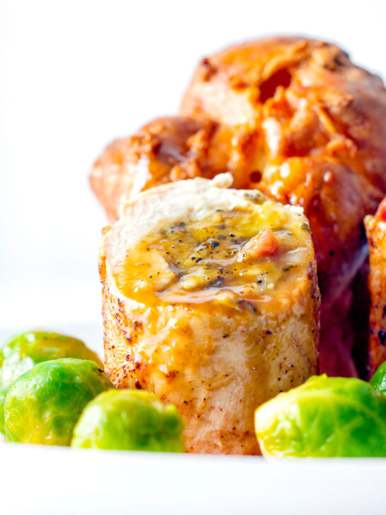 Close up sage and onion stuffed chicken ballotine served with gravy and sprouts.