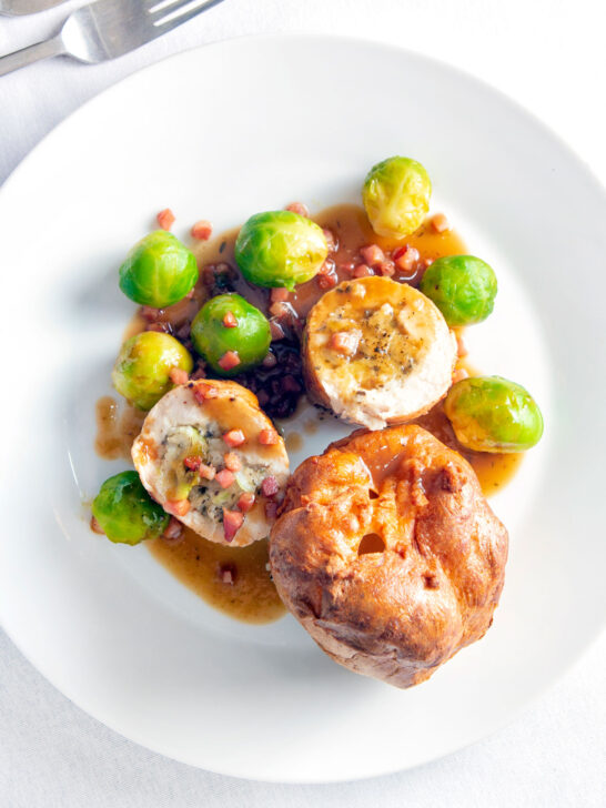 Overhead sage and onion stuffed chicken ballotine served with gravy, Yorkshire pudding & sprouts.