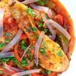 Close up overhead chicken Basque with peppers and tomatoes.