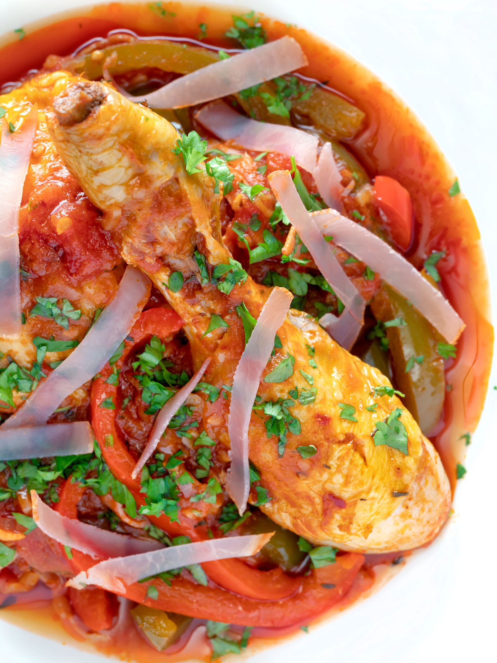 Close up overhead chicken Basque with peppers and tomatoes.