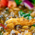 Close up chicken dhansak lentil curry with kachumber salad.