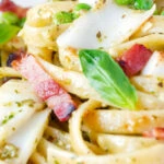 Close up cod pasta with pesto, peas and bacon.