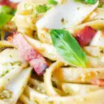 Close up cod pasta with pesto, peas and bacon featuring a title overlay.