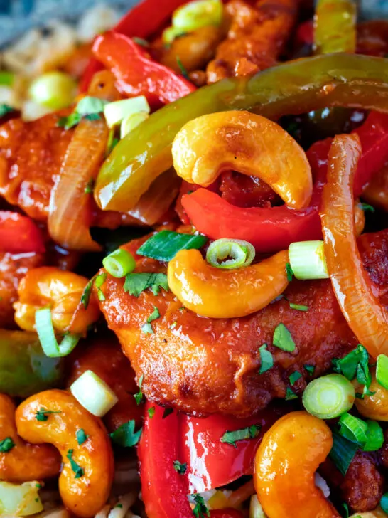 Close up dragon chicken with peppers and cashew nuts served with egg fried rice.