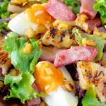 Close up gammon salad with seared pineapple, boiled eggs and potatoes featuring a title overlay.