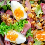 Close up overhead gammon salad with seared pineapple, boiled eggs and potatoes.