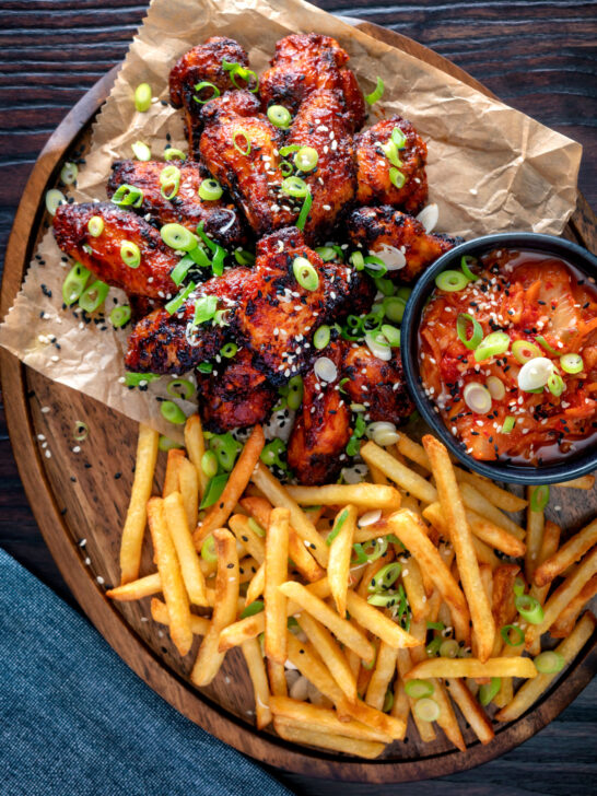 Overhead Korean influenced chicken wings served with fries and kimchi.