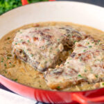 Normandy pork chops in a creamy cider and apple sauce in an enamel cooking pan.