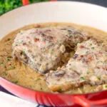 Normandy pork chops in a creamy cider and apple sauce in an enamel cooking pan.