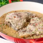 Normandy pork chops in a creamy cider and apple sauce in an enamel cooking pan featuring a title overlay.