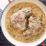 Overhead Normandy pork chops in a creamy cider and apple sauce in an enamel pan featuring a title overlay.