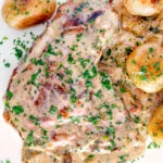 Overhead thick cut Normandy pork chops in a creamy cider sauce with potatoes.