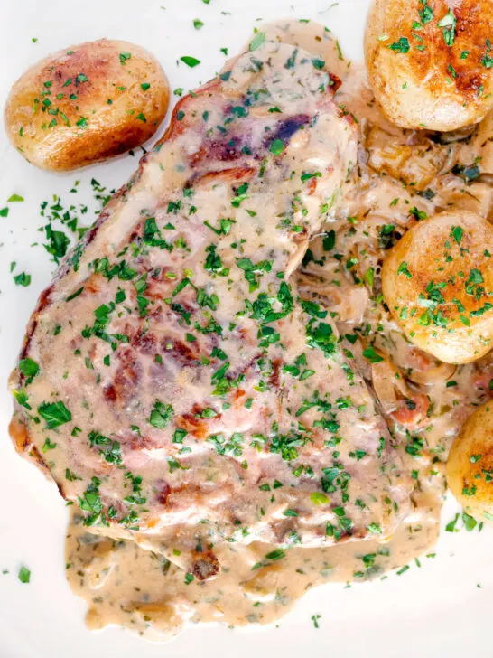Overhead thick cut Normandy pork chops in a creamy cider sauce with potatoes.