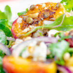 Close up peach and feta cheese salad with puy lentils and rocket or arugula.