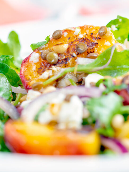 Close up peach and feta cheese salad with puy lentils and rocket or arugula.